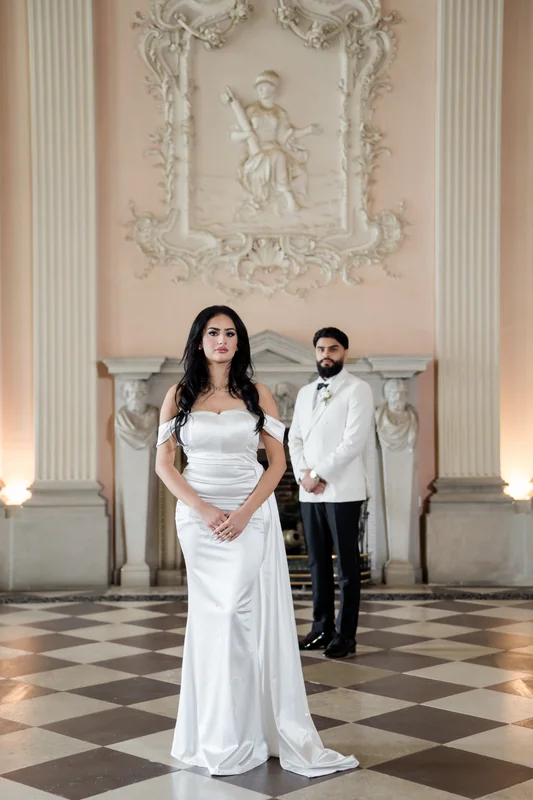 The couple standing beneath decorative plasterwork
