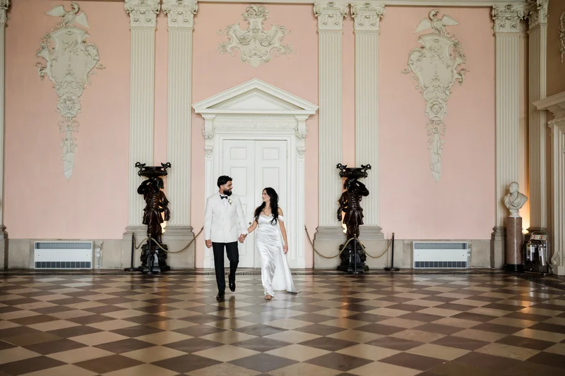 The couple standing together in the ornate room