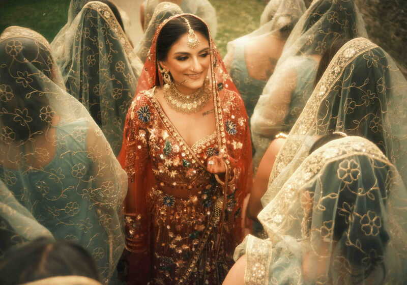 Bride in red wedding attire surrounded by embroidered veils