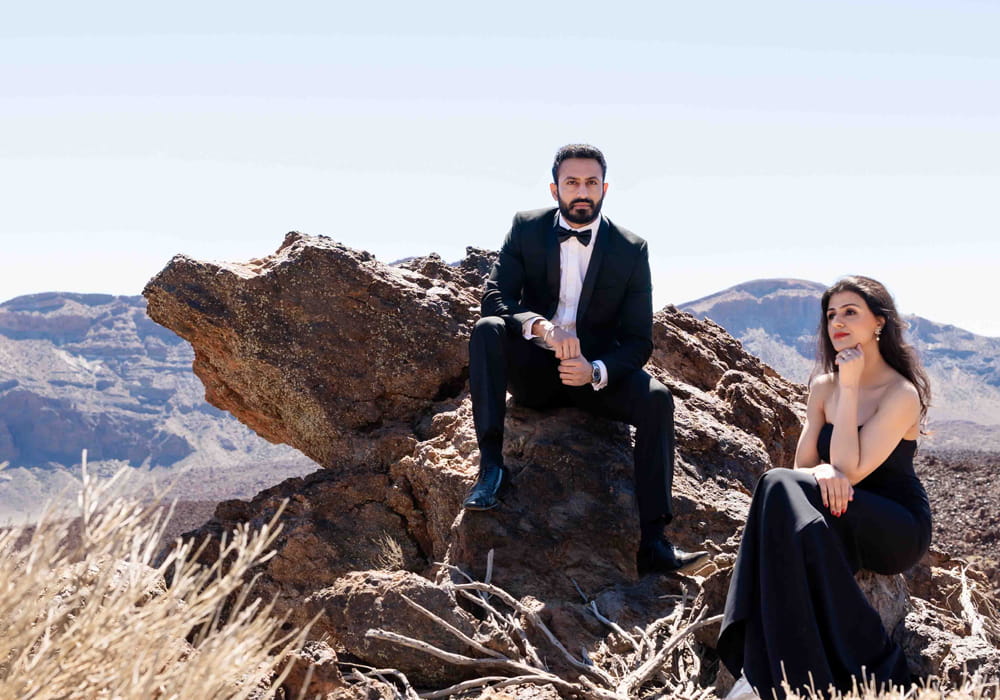 Couple in formal attire photographed together in a mountain landscape